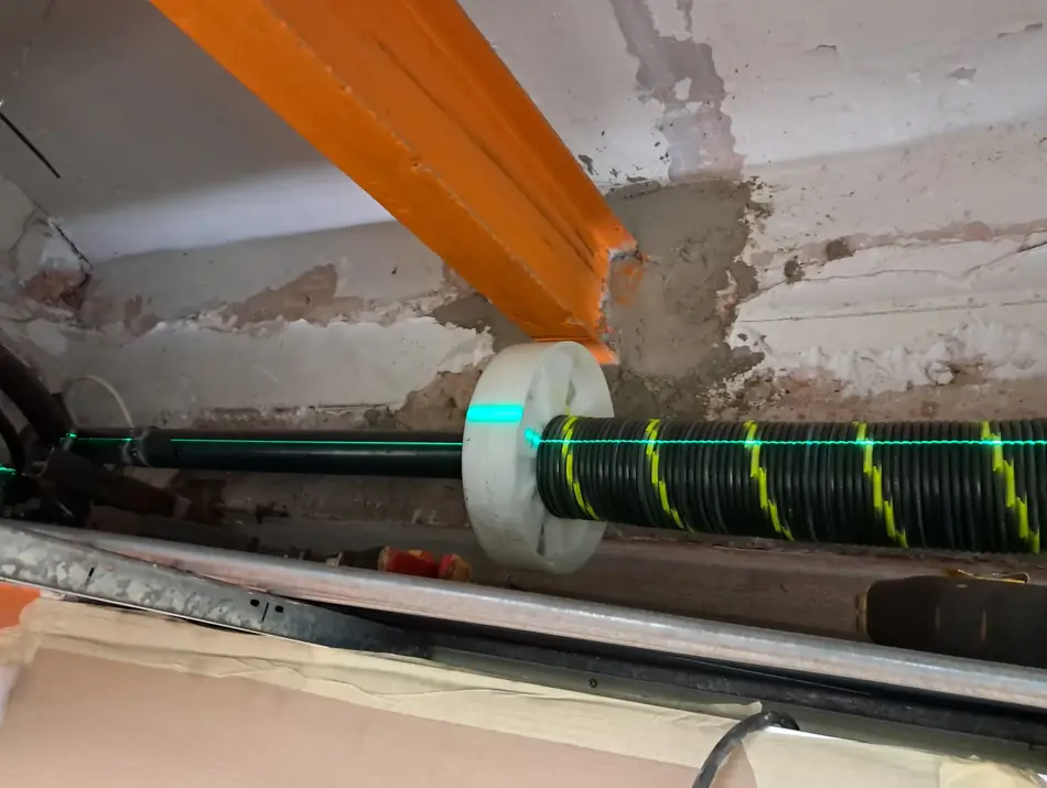 Eje nuevo de persiana durante el montaje, comprobando el nivel con un láser
