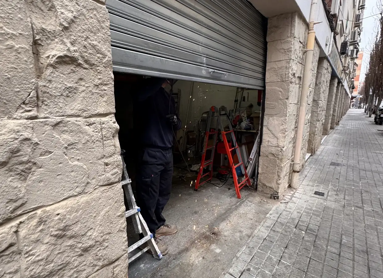 Técnico trabajando en el cierre metálico de un local, en una calle de Barcelona